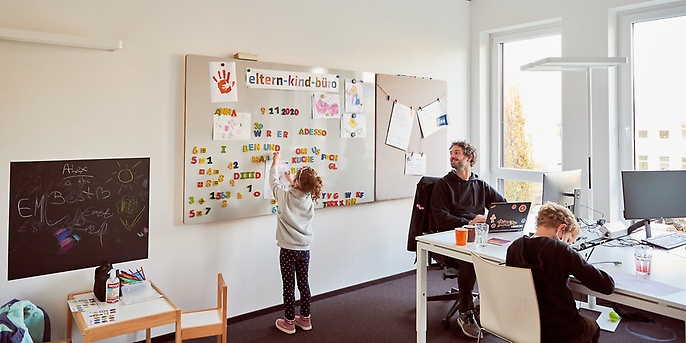 Ein Mitarbeiter ist mit Kindern im Eltern-Kind-Büro